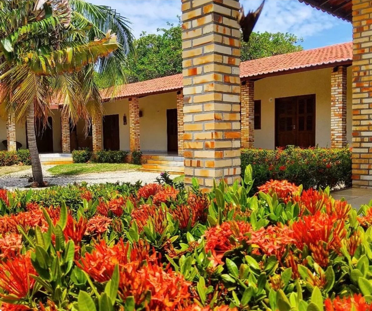 Suítes da Vila dos Oito com colunas de tijolo e flores tropicais